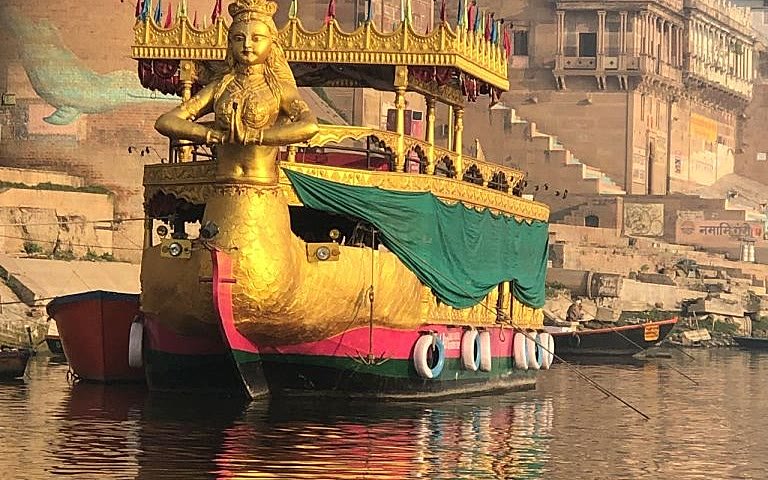 A gilded ceremonial boat on the Ganga at Varanasi, reflected in the morning water
